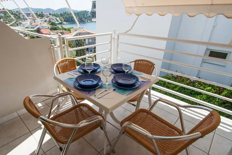 A balcony table set for four, with the sea beyond